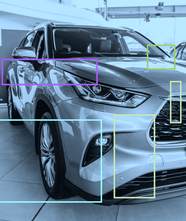 Close-up showroom photo of a silver SUV with VisionAI overlays on the door, grille, bumper, hood, and wheel.